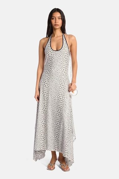 Woman in a halter neck dress with a dotted pattern and asymmetrical hemline.